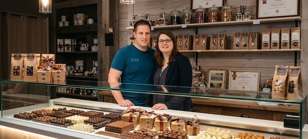 Les deux fondateurs souriants derrière le comptoir de pralines et chocolats artisanaux en 2017.